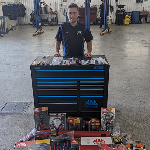 SCADT Apprentice standing behind the tool box and tools received through the scholarship